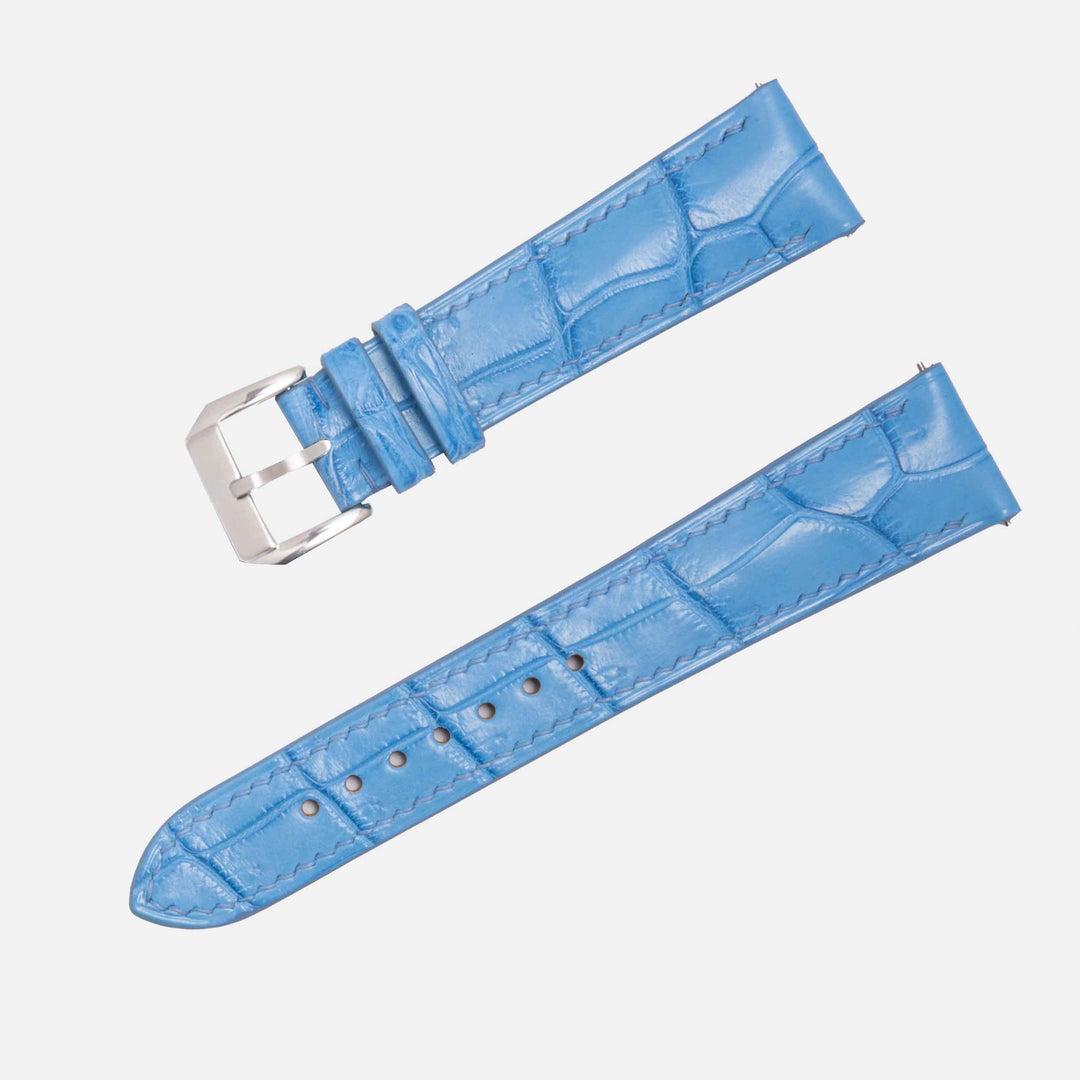Blue crocodile-patterned watch strap with silver buckle on a white background