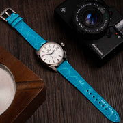 Grand Seiko Snowflake with blue strap and camera on a wooden surface